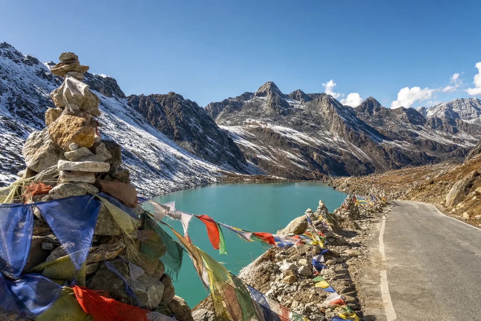 Prayer flags over a turquoise lake at a high Himalayan pass