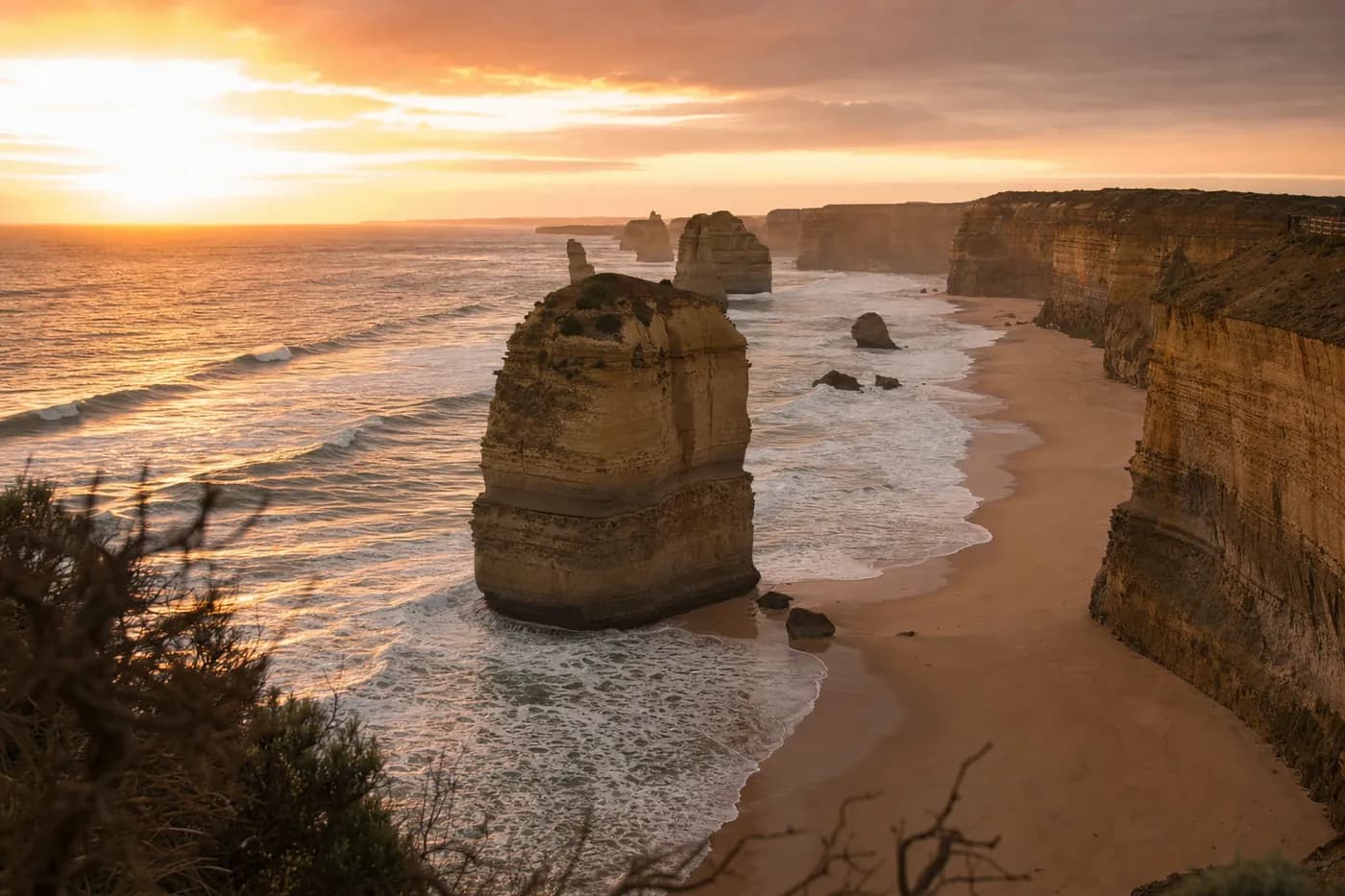 Golden limestone sea stacks off a rugged coast at sunset