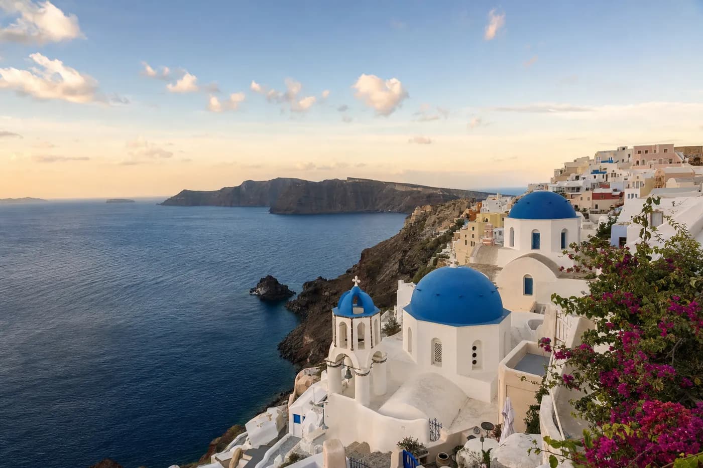 Whitewashed houses and blue domes above the Aegean at golden hour