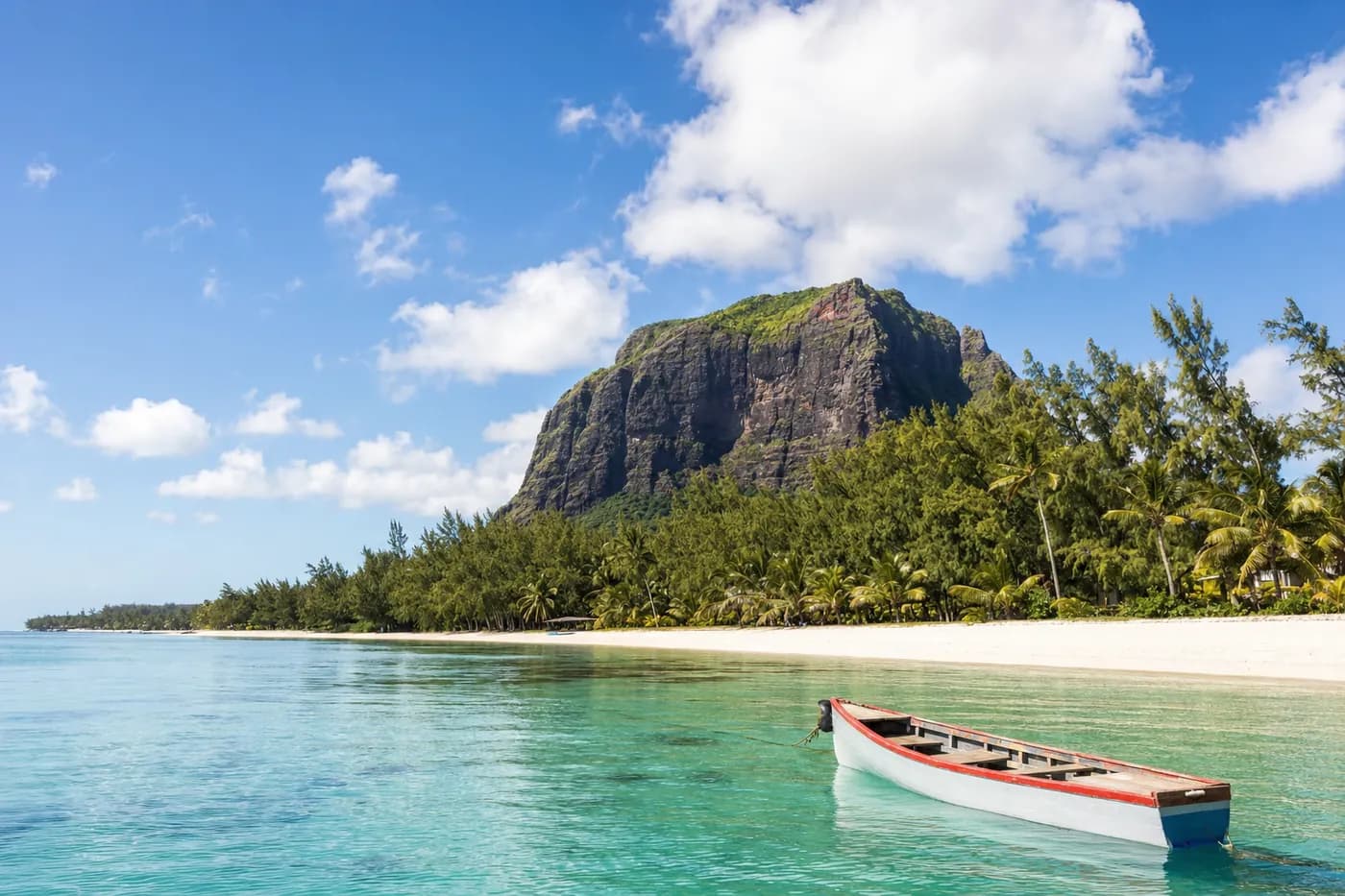 A calm lagoon beneath a basalt mountain with a small wooden boat