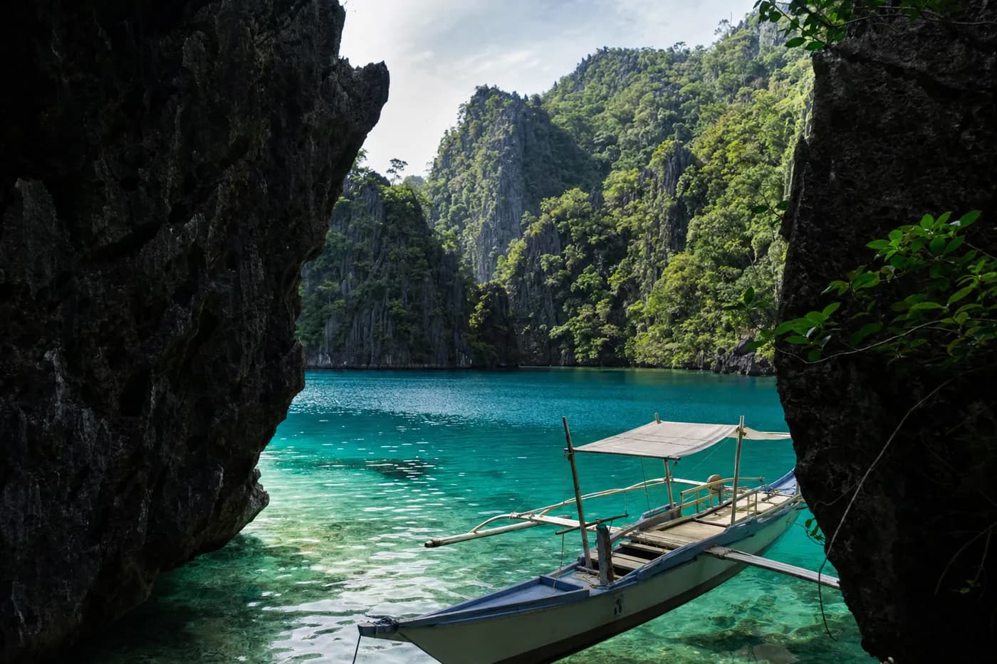 A hidden lagoon with limestone cliffs and an outrigger boat