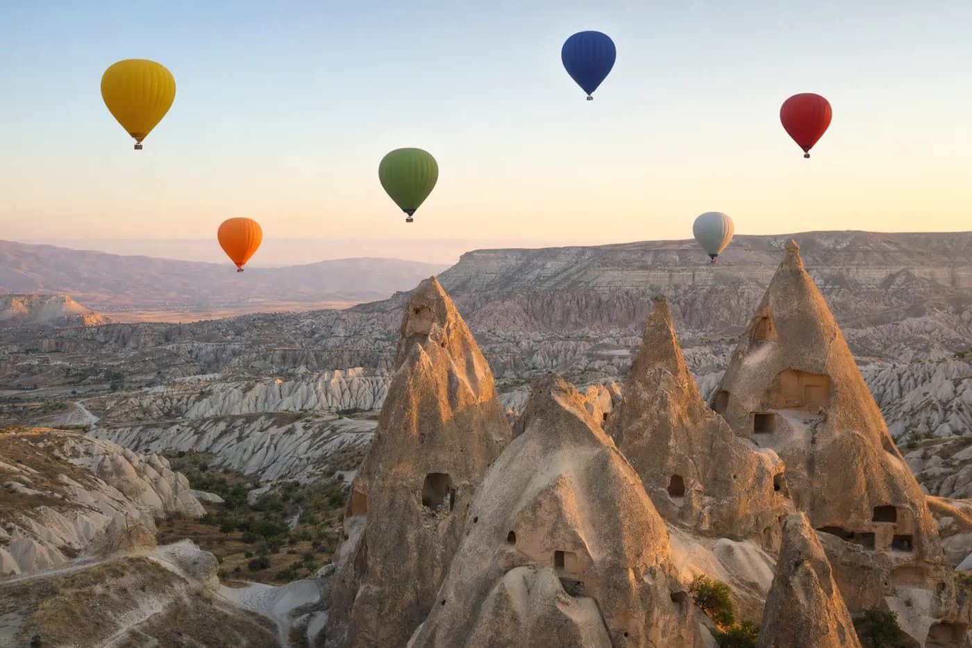 Fairy chimneys in Cappadocia at sunrise with hot-air balloons