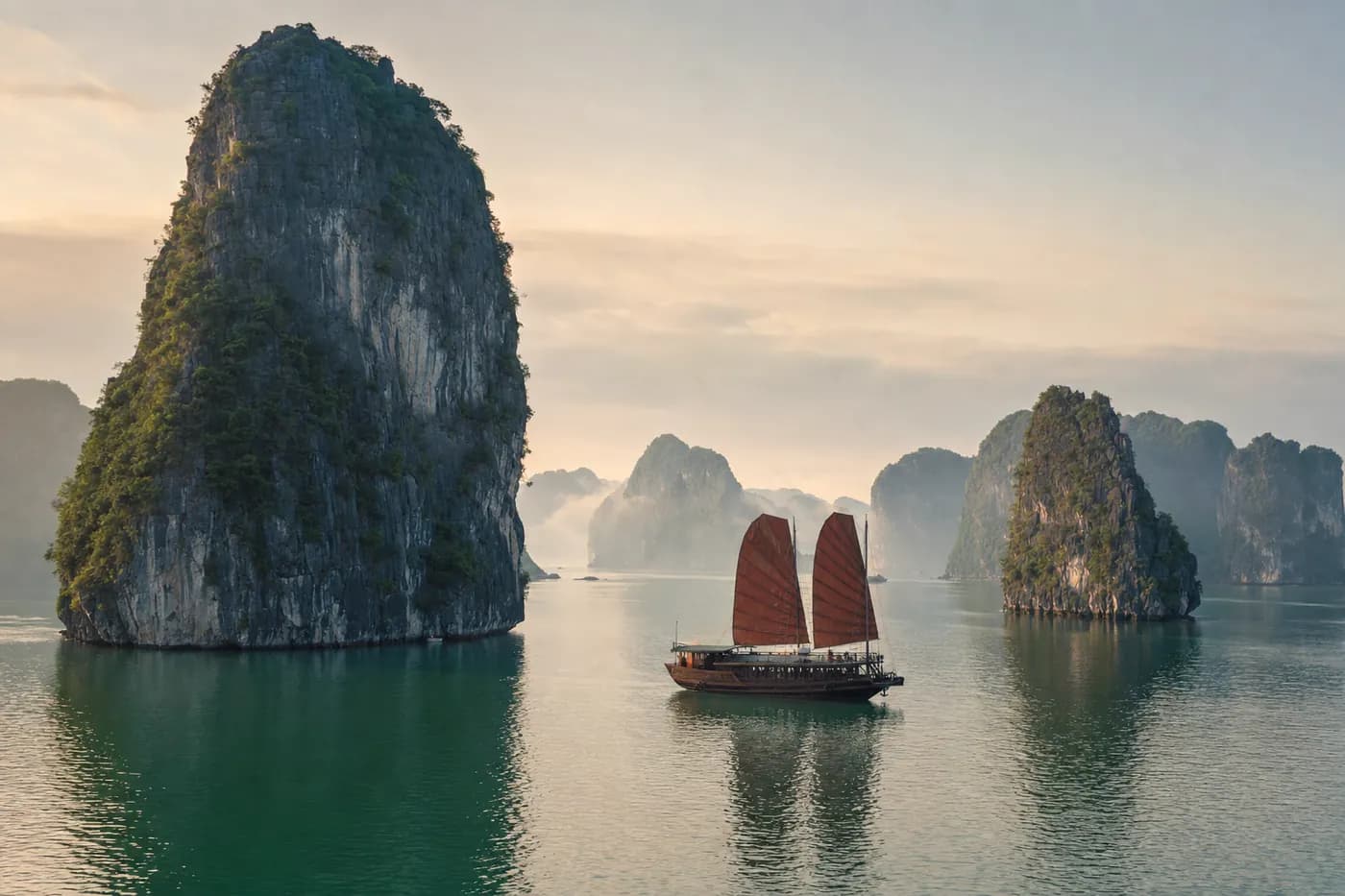 Limestone karst islands in a calm bay with a traditional junk boat