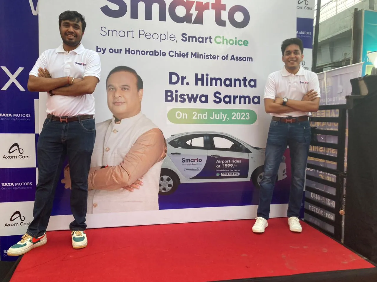 Shashank and Manav Bajoria in Smarto shirts on either side of the Smarto launch banner